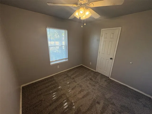 an empty room with windows and chandelier fan