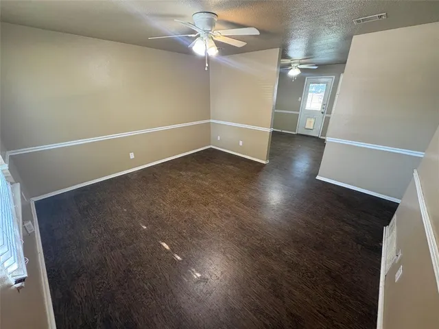 en empty room with wooden floor and fan