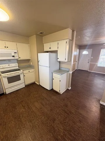 a view of a kitchen with refrigerator and wooden floor