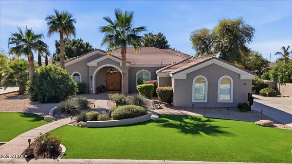 a front view of a house with garden and trees