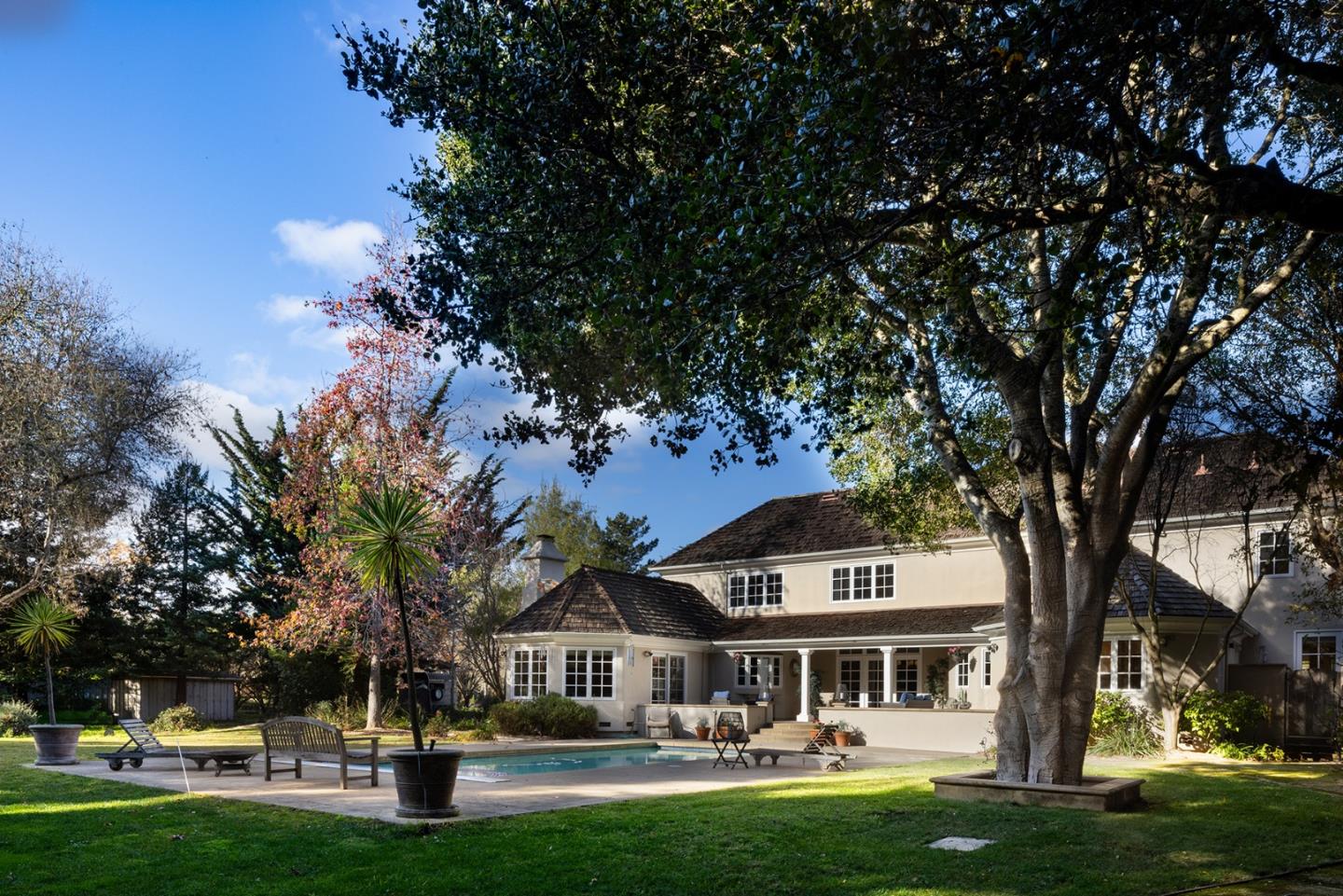 a front view of a house with garden and trees