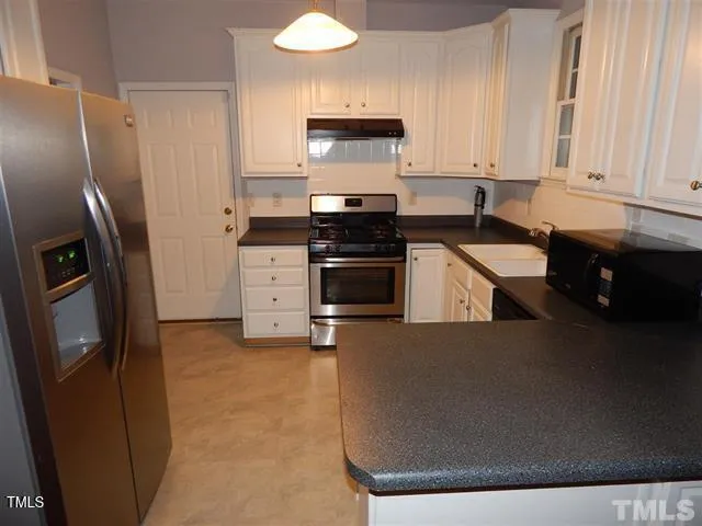 a kitchen with granite countertop a refrigerator stove and sink