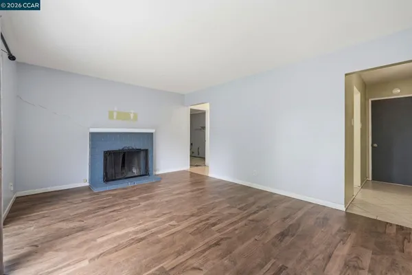 a view of empty room with wooden floor and fireplace