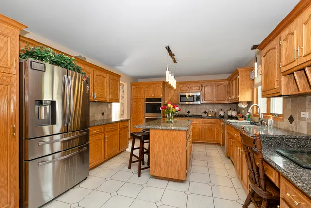 a kitchen with stainless steel appliances granite countertop a refrigerator and a stove top oven