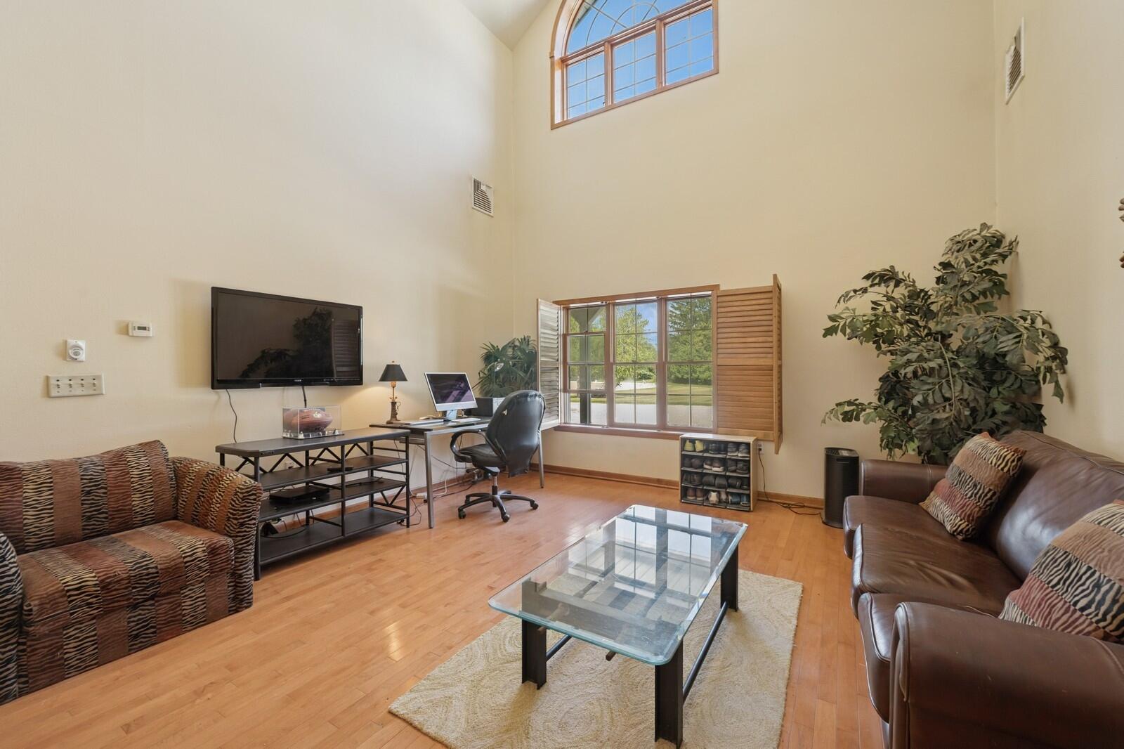 W1800 County Road B Bloomfield, WI 53128 - Photo 14 of 81 Bright living area with vaulted ceiling, hardwood flooring, and large windows, offering a comfortable space for relaxation or home office use.