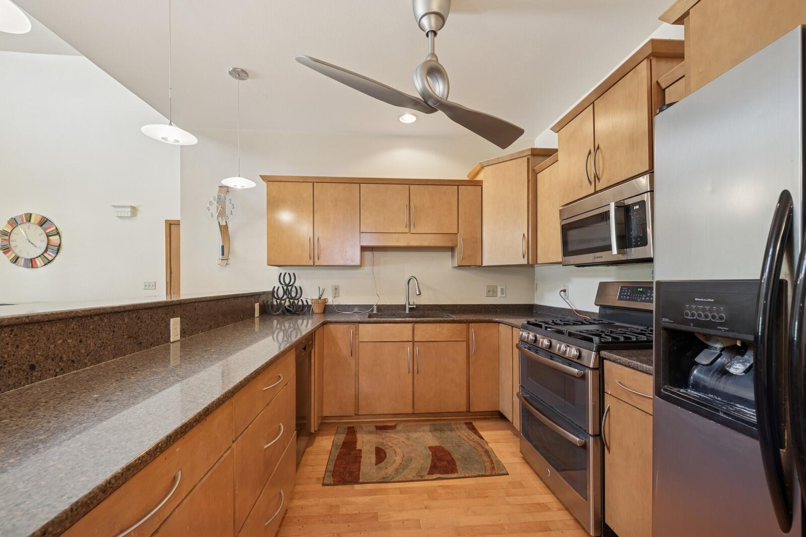 W1800 County Road B Bloomfield, WI 53128 - Photo 16 of 81 Well-equipped kitchen with stone countertops, stainless steel appliances, gas range, and modern lighting, designed for efficiency and style.