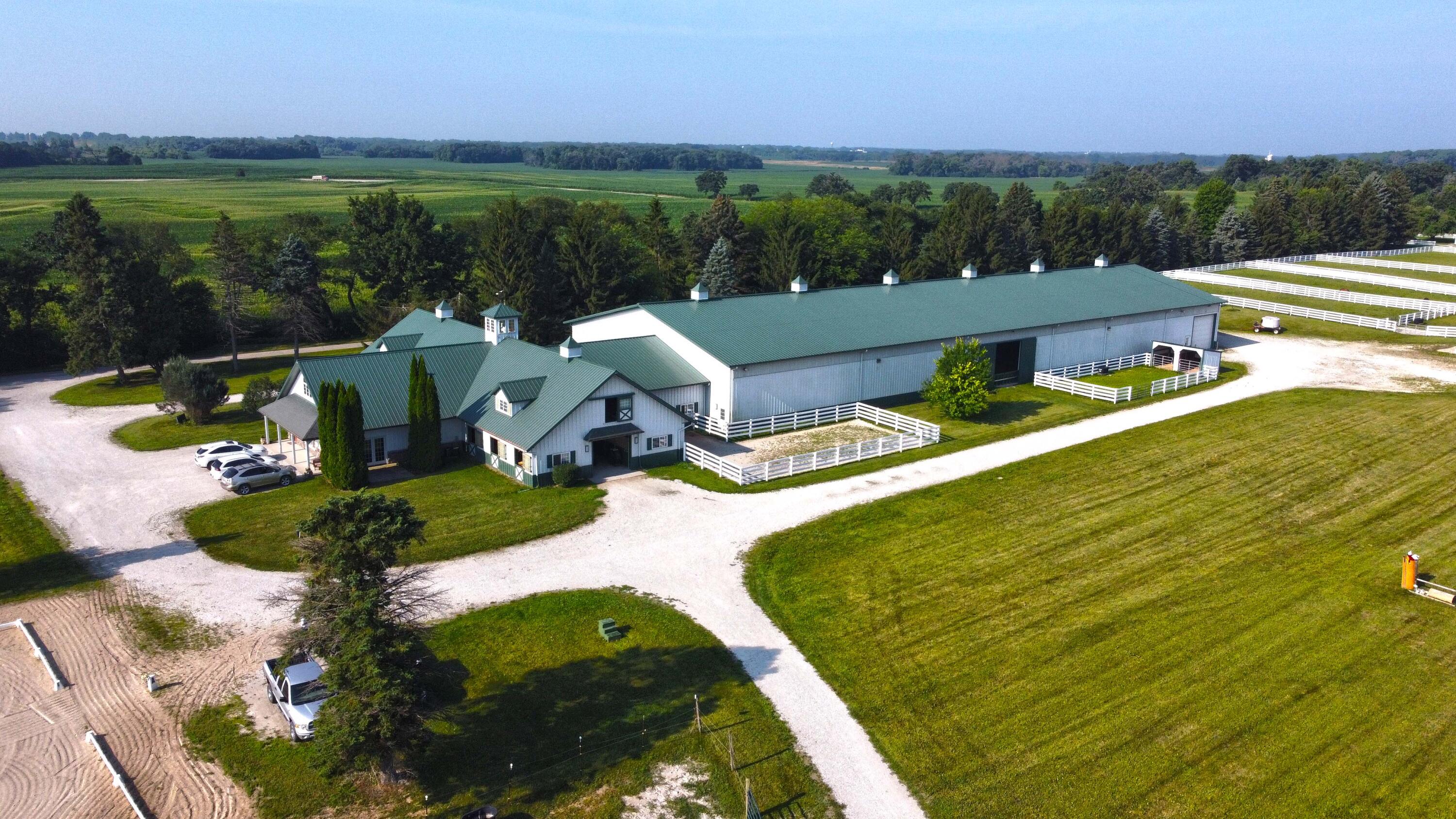 W1800 County Road B Bloomfield, WI 53128 - Photo 2 of 81 Aerial view of the professionally designed equestrian center featuring an 80’ x 240’ indoor riding arena, adjacent barns, gravel drives, and fenced training areas set amid open countryside.