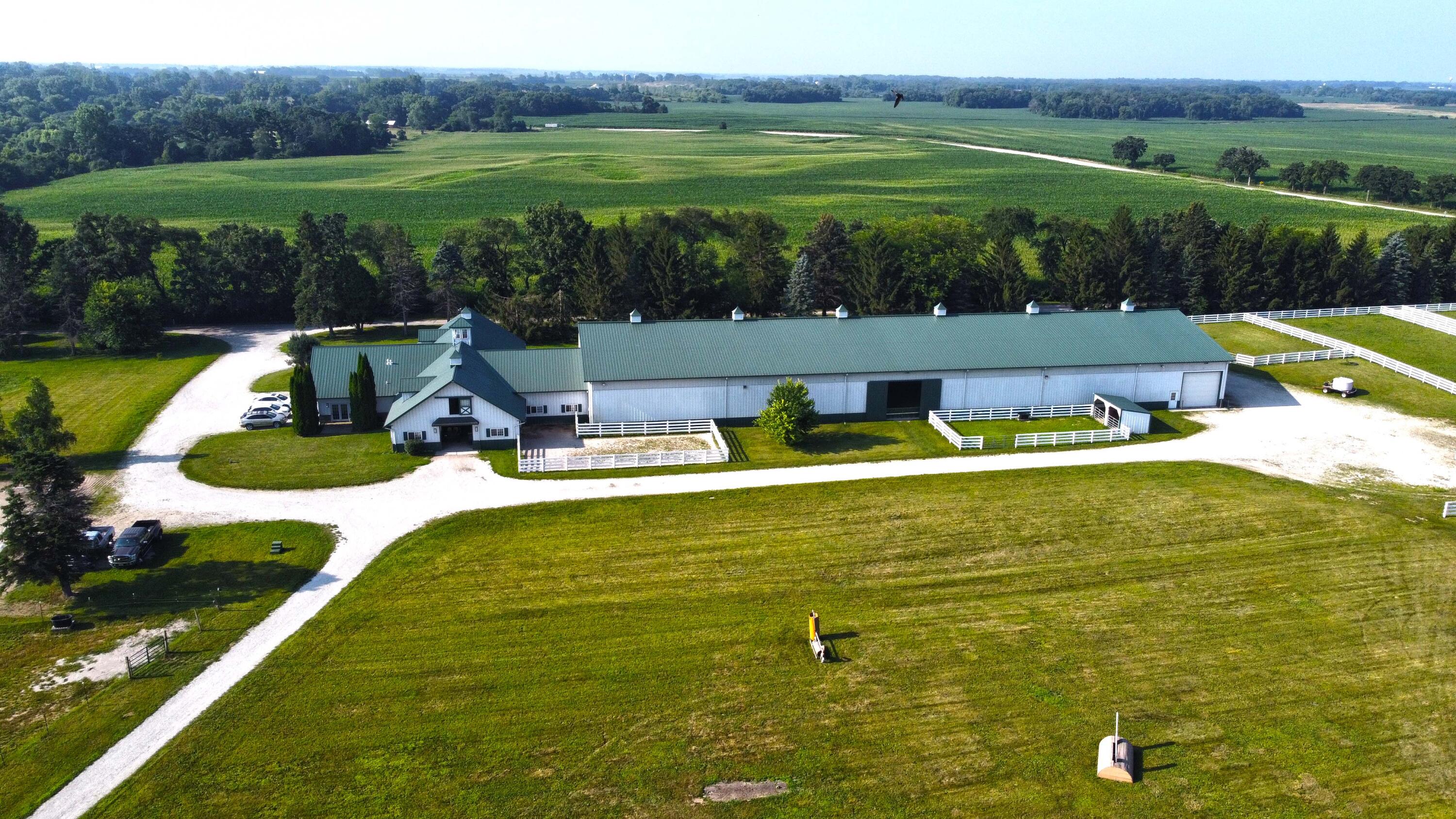 W1800 County Road B Bloomfield, WI 53128 - Photo 21 of 81 Wide view highlighting the indoor riding arena alongside the outdoor sand ring, with direct access to fenced paddocks and nearby pastures for efficient training flow.