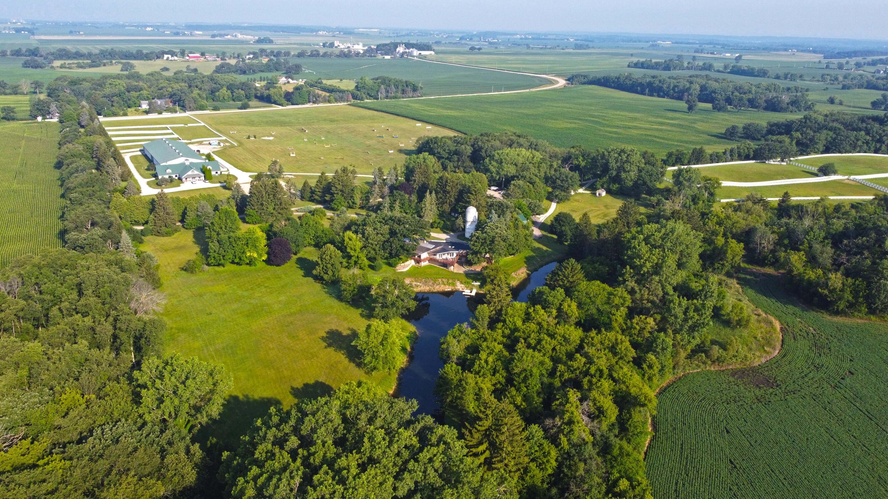 W1800 County Road B Bloomfield, WI 53128 - Photo 23 of 81 Wide property view highlighting the relationship between the main house, equestrian facilities, fenced pastures, and surrounding farmland.