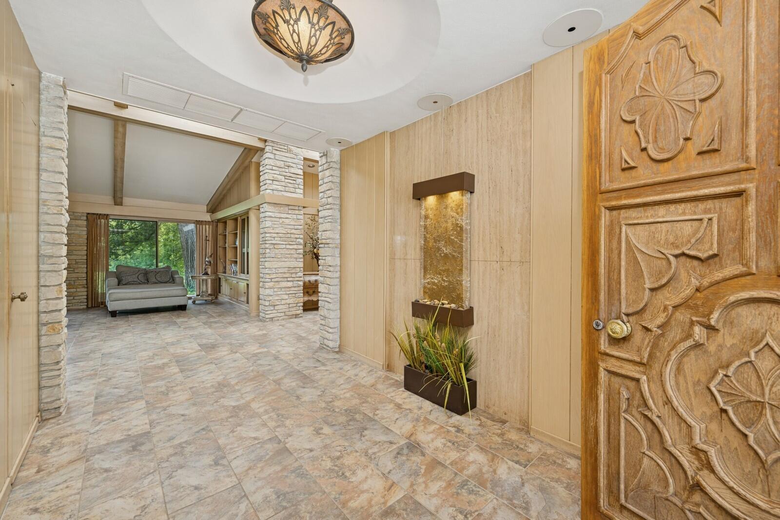 W1800 County Road B Bloomfield, WI 53128 - Photo 26 of 81 A welcoming entry foyer with tiled flooring, stone accents, and a custom carved wood front door that sets the tone for the home’s architectural character.