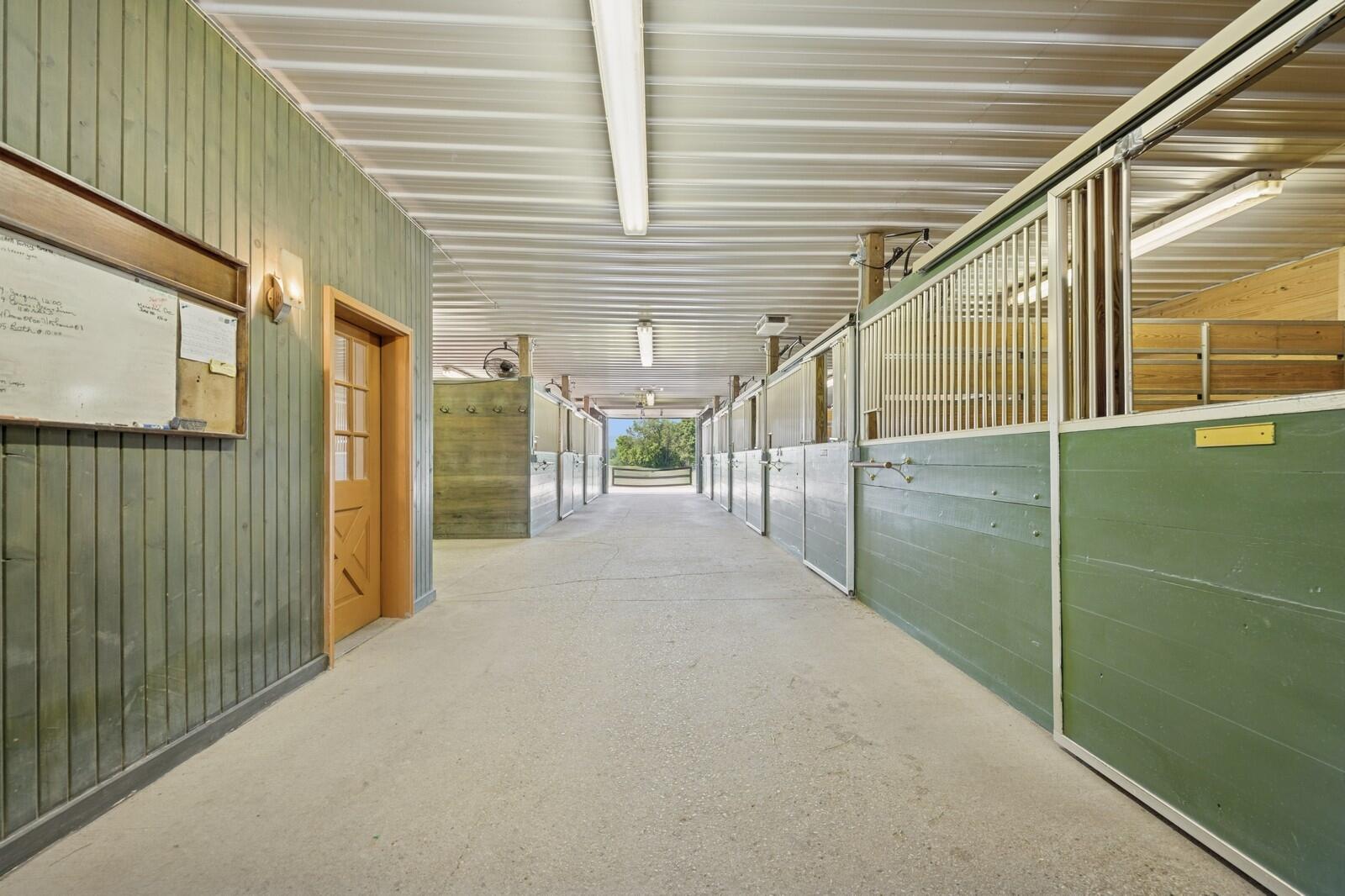 W1800 County Road B Bloomfield, WI 53128 - Photo 3 of 81 Wide center aisle with heated concrete flooring, overhead lighting, and easy access to individual stalls on both sides