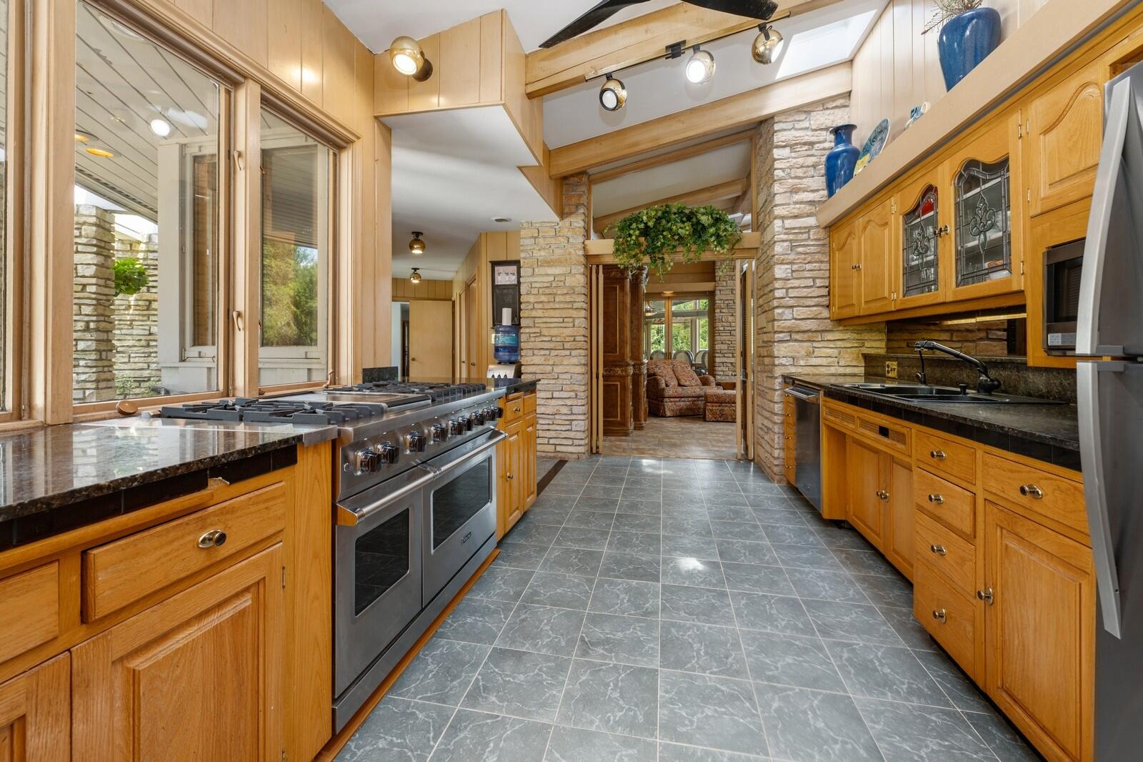 W1800 County Road B Bloomfield, WI 53128 - Photo 37 of 81 Well-appointed kitchen featuring wood cabinetry, stone countertops, tile flooring, and a professional-style gas range, designed for both functionality and flow.