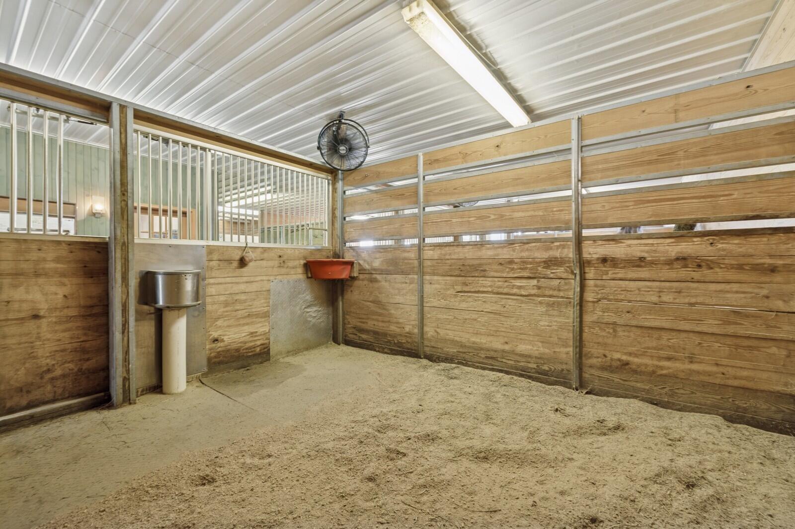 W1800 County Road B Bloomfield, WI 53128 - Photo 4 of 81 Well-appointed horse stall featuring heated floors, rubber mat flooring, individual overhead fan, on-demand Nelson automatic watering system, and a Pyranha Spray Master misting system, designed for comfort, cleanliness, and efficient daily care.