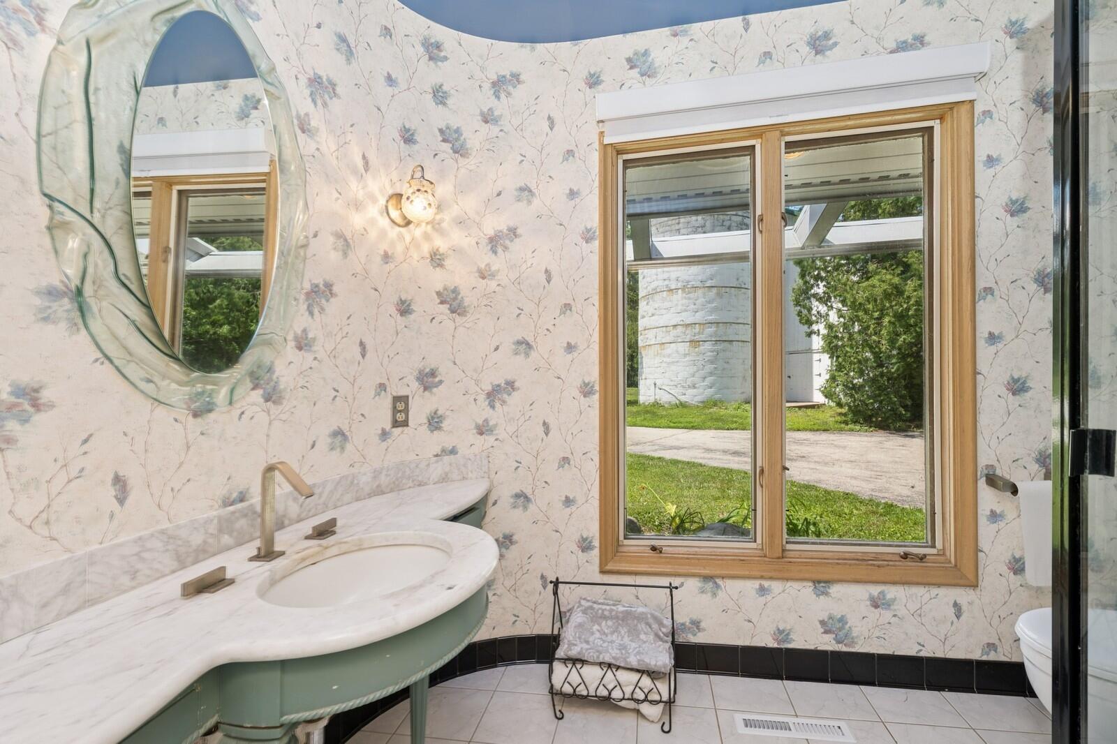 W1800 County Road B Bloomfield, WI 53128 - Photo 49 of 81 A light-filled main level full guest bathroom featuring a custom vanity, sunken shower, and window overlooking the surrounding grounds.