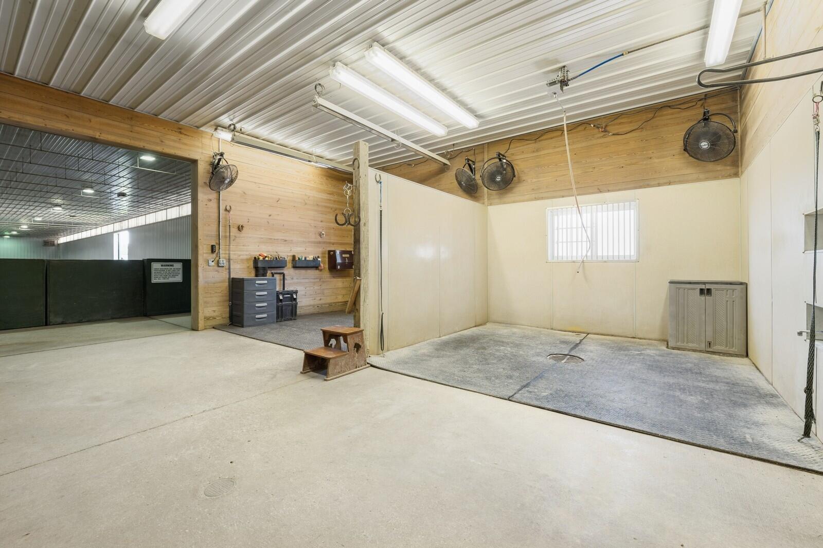 W1800 County Road B Bloomfield, WI 53128 - Photo 5 of 81 Dedicated wash and grooming stall featuring rubber mat flooring, wall-mounted fans, and ample working space. Conveniently located between stalls and arena.