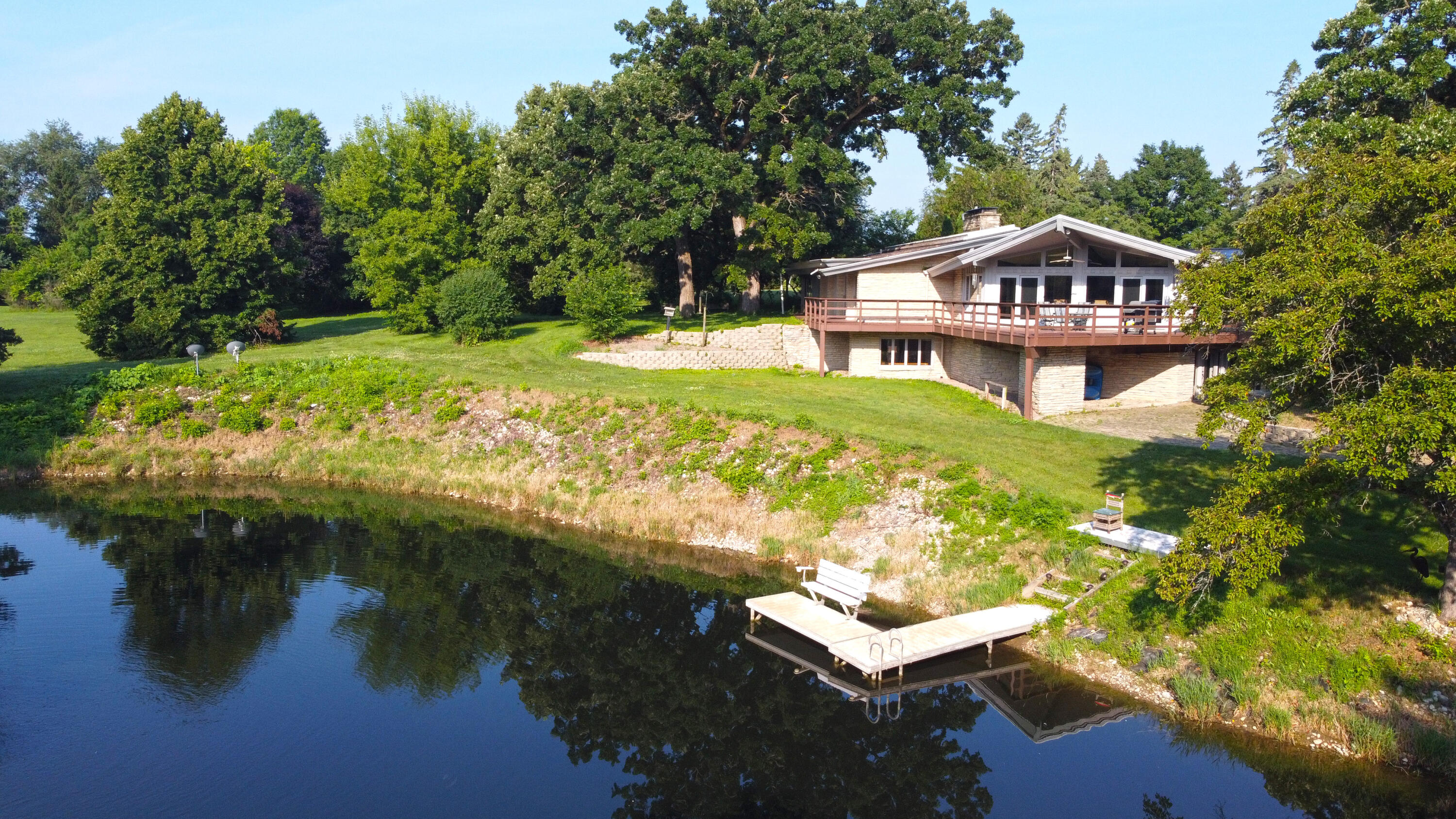 W1800 County Road B Bloomfield, WI 53128 - Photo 57 of 81 View highlighting the private dock, pond frontage, and elevated deck, offering a strong connection between indoor and outdoor living.