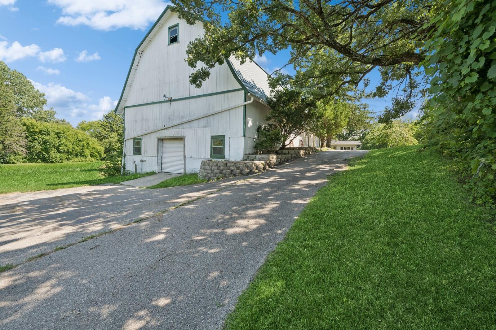 W1800 County Road B Bloomfield, WI 53128 - Photo 62 of 81 Paved drive leading to the barn with retaining walls and mature landscaping, providing convenient access for vehicles and equipment.