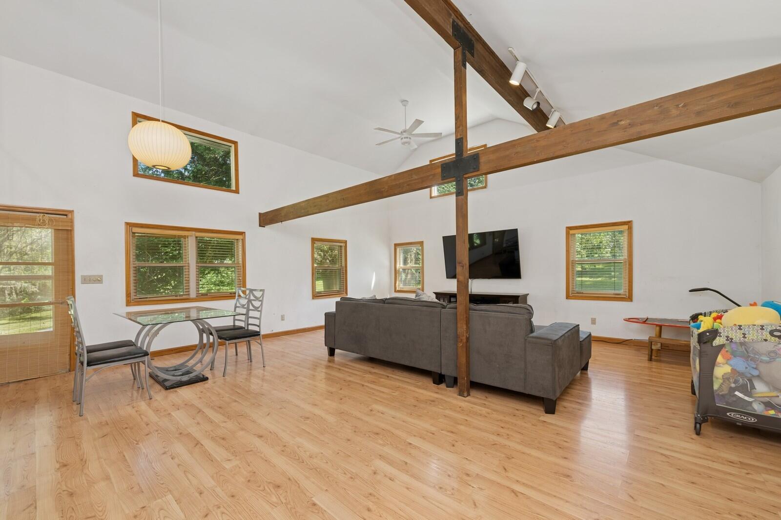 W1800 County Road B Bloomfield, WI 53128 - Photo 67 of 81 Bright, open living space with vaulted ceiling, exposed beams, hardwood flooring, and flexible layout for seating and dining.
