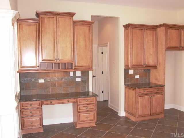 2204 Clayette Court Raleigh, NC 27612 - Photo 6 of 10 Built in planning center is to the left in the kitchen. Passageway leads to well sized powder room and large laundry room with Maple cabinets above W/D. Has utility sink and broom closet. Between the two is exit to finished garage.