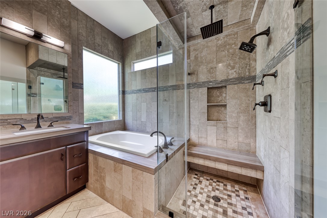 2122 Mooreview Street Henderson, NV 89012 - Photo 21 of 44 A well-appointed primary bath features a spacious walk-in shower with a rain shower head and a built-in bench alongside a large soaking tub.