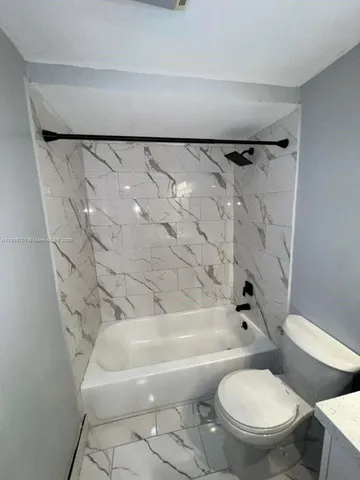 a white toilet sitting next to a bath tub and a shower