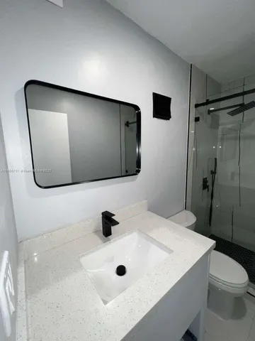 a bathroom with a sink a toilet and shower