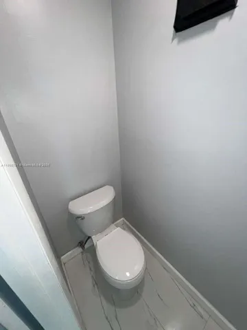 a white toilet sitting next to a white wall