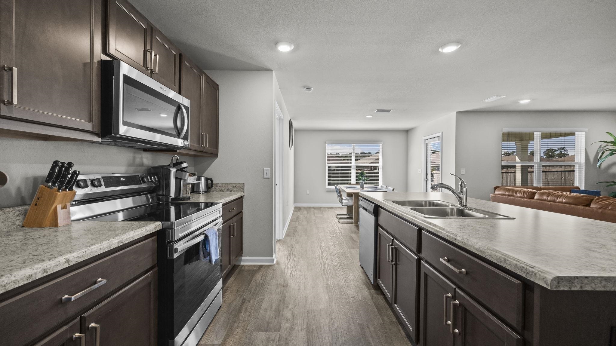 224 Burnston Way Foley, AL 36535 - Photo 17 of 42 Kitchen featuring stainless steel appliances, dark brown cabinetry, dark wood-style flooring, an island with sink, and recessed lighting