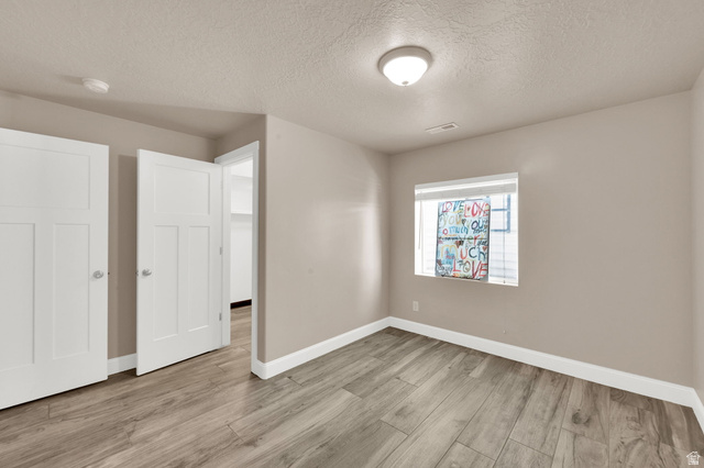 1857 Thunder Gulch Road Eagle Mountain, UT 84005 - Photo 36 of 50 Spacious room featuring neutral tone walls, wood-finish flooring, white trim, and a window with blinds