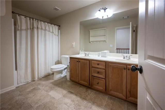 a spacious bathroom with a double vanity sink toilet and a mirror