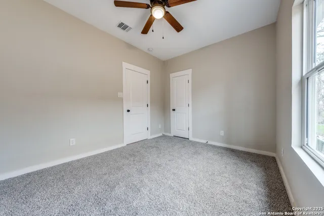 an empty room with a window and a ceiling fan