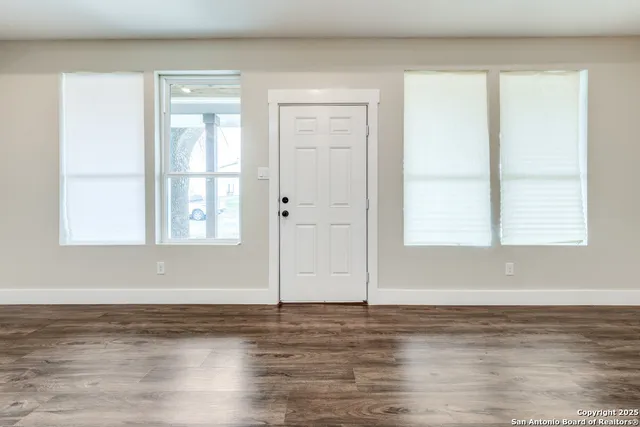 a view of empty room with window and wooden floor