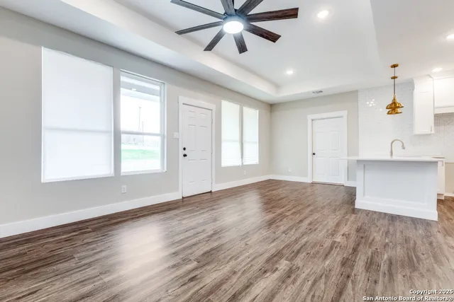a view of an empty room with window and wooden floor