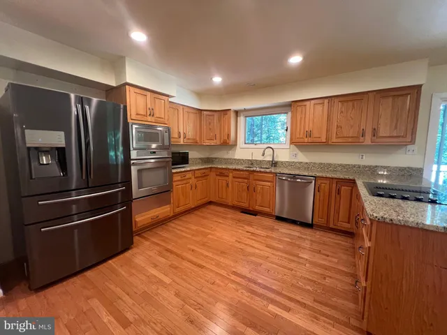 a kitchen with stainless steel appliances granite countertop a refrigerator a sink dishwasher a stove top oven a sink and dishwasher