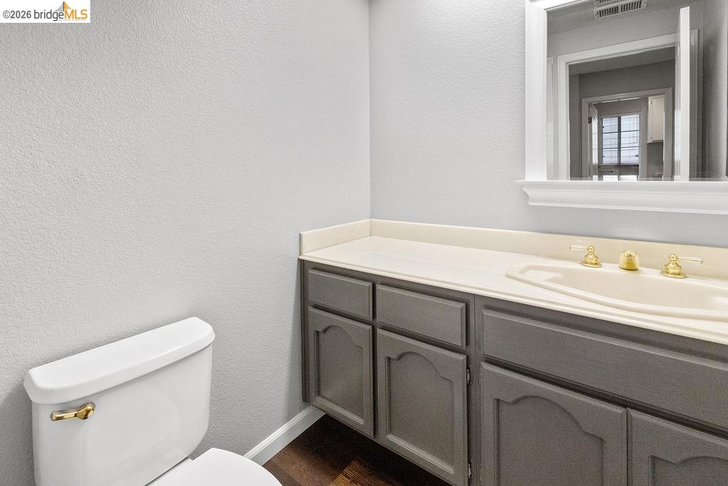 724 Winterside Circle San Ramon, CA 94583 - Photo 16 of 43 Bathroom featuring a white toilet with a brass-finish handle, a vanity with a light-toned countertop, an integrated sink, brass-finish faucet fixtures, and gray cabinetry