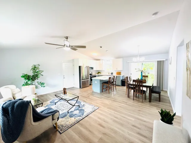 a living room with furniture and a dining table with potted plants