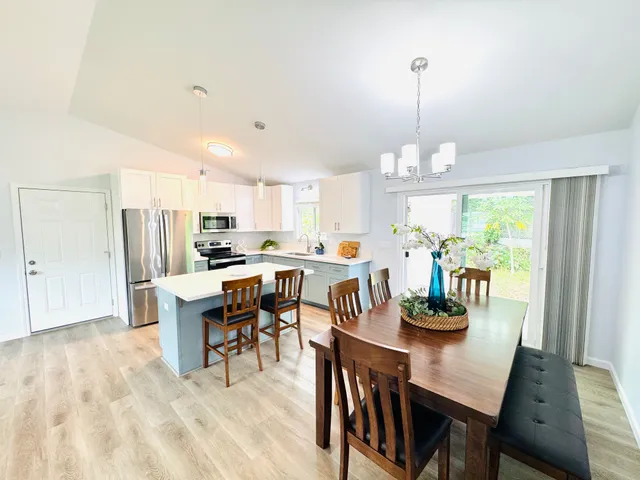 a view of a dining room and livingroom with furniture wooden floor a chandelier