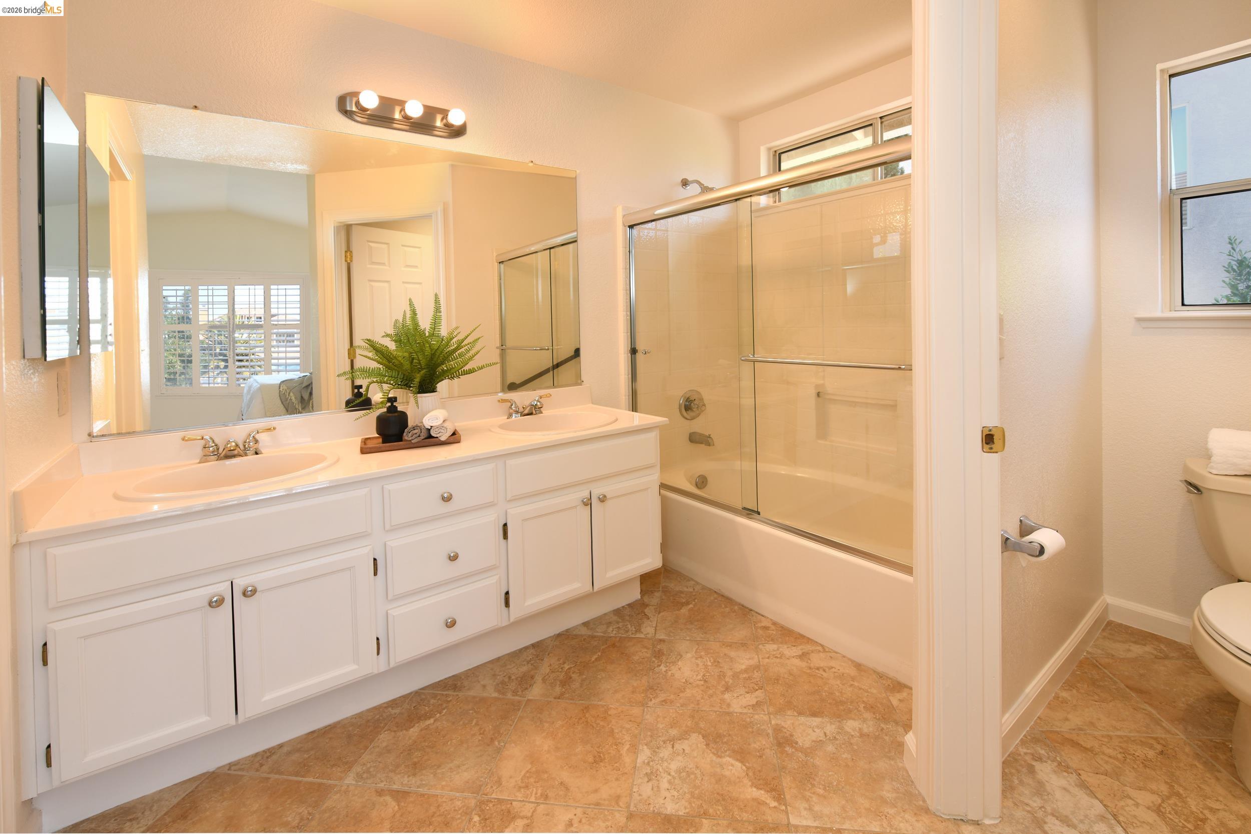 512 Burdick Drive Bay Point, CA 94565 - Photo 27 of 50 Dual vanity with white cabinetry and integrated sinks, a full-width mirror, and a three-light fixture