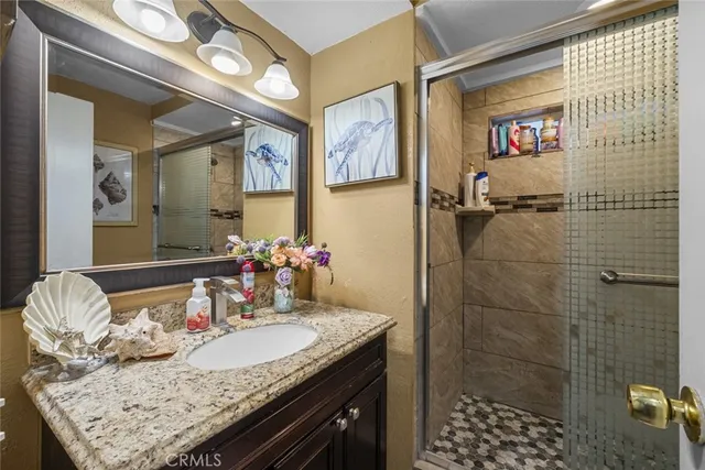 a bathroom with a granite countertop sink a mirror and shower
