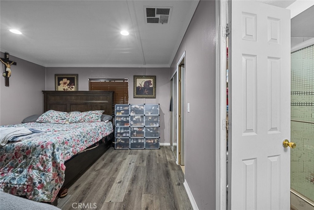 3255 East Avenue R, Unit 34 Palmdale, CA 93550 - Photo 16 of 32 a bedroom with a large bed and a wooden floor