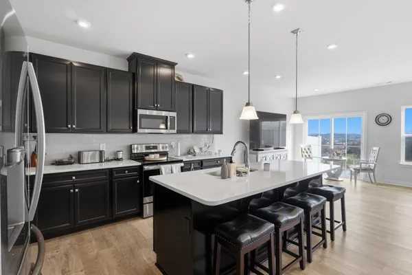 a kitchen with a sink a center island stainless steel appliances and cabinets