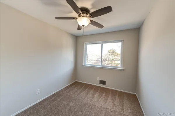 an empty room with a window and a fan