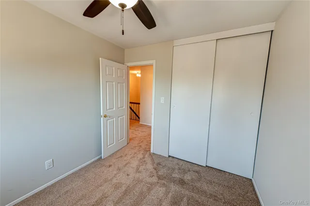 an empty room with closet and a chandelier fan