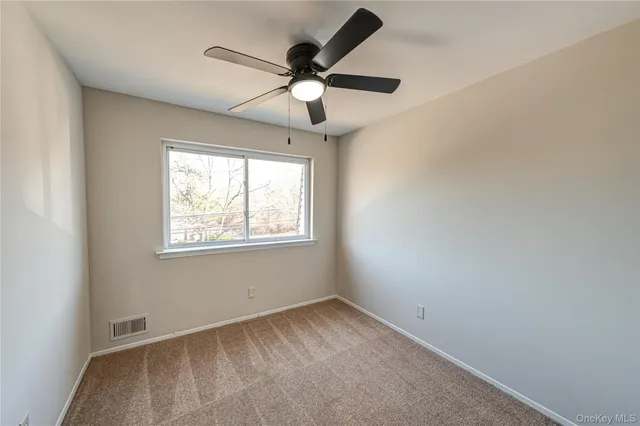 an empty room with a window and a fan