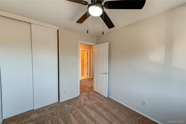 a view of empty room with window and chandelier fan