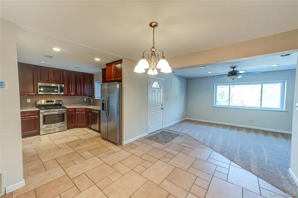 a kitchen with stainless steel appliances granite countertop a refrigerator a sink dishwasher a stove with wooden cabinets and floor