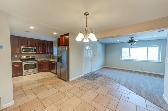 a kitchen with stainless steel appliances granite countertop a refrigerator a sink dishwasher a stove with wooden cabinets and floor