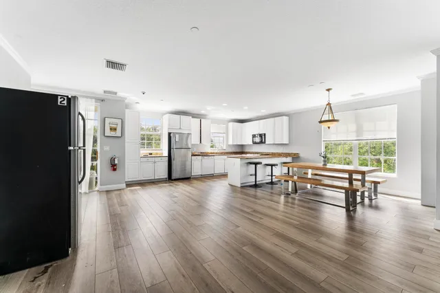 a living room with furniture and a kitchen view with wooden floor