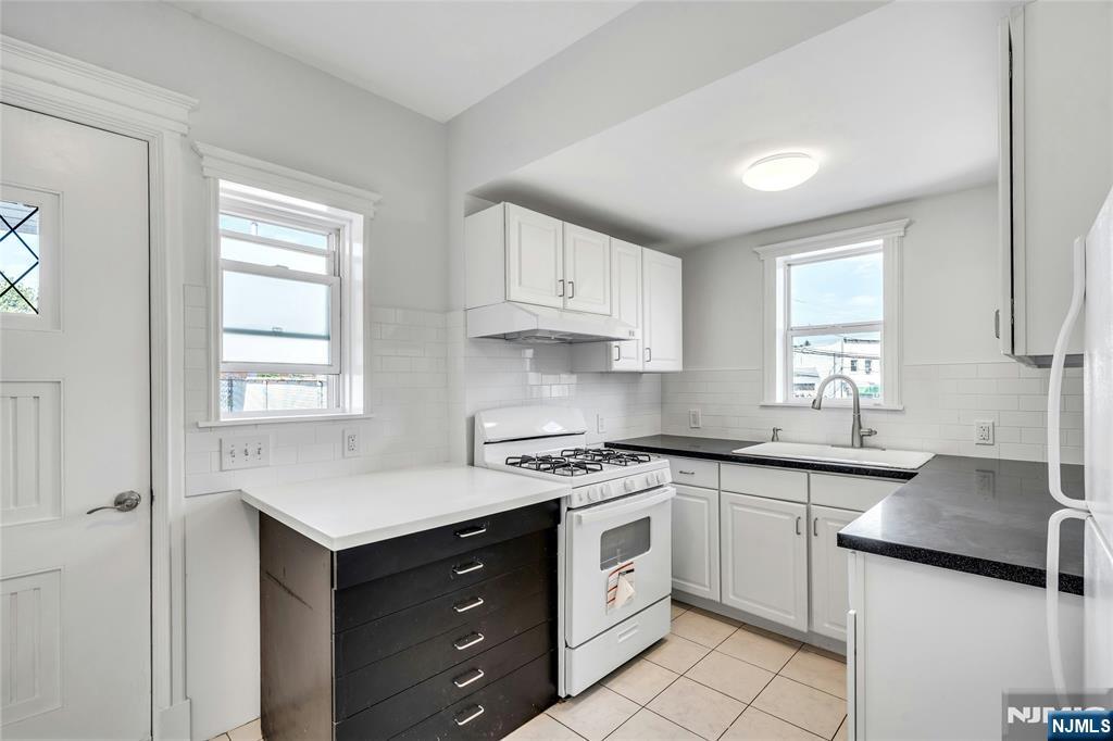 425 Hancock Place Fairview, NJ 07022 - Photo 11 of 31 a kitchen with white cabinets appliances a sink and a window