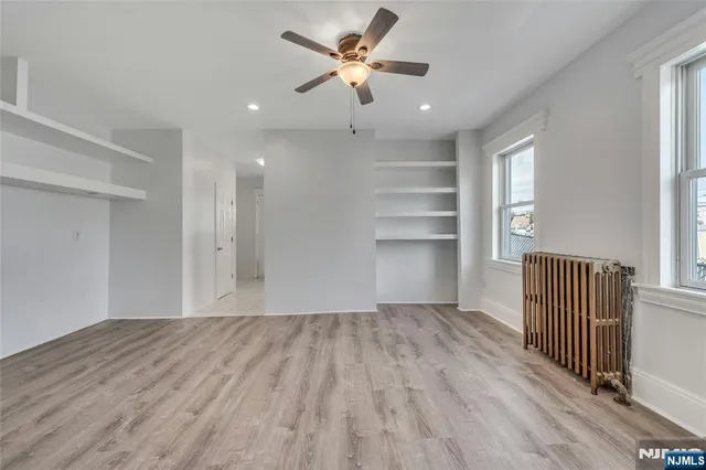 a view of an empty room with a window and wooden floor